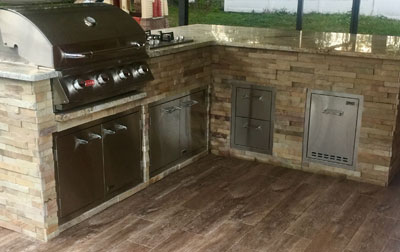 An L-shaped outdoor kitchen equipped with a Lion BBQ Grill.