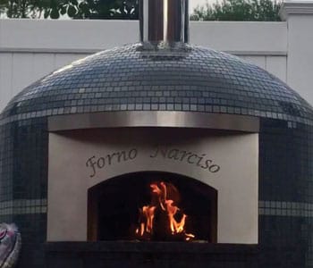 An outdoor pizza oven with a glass tile finish and a custom engraving