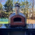 A Forno Nardona Rustico Model pizza oven sits atop an outdoor kitchen.