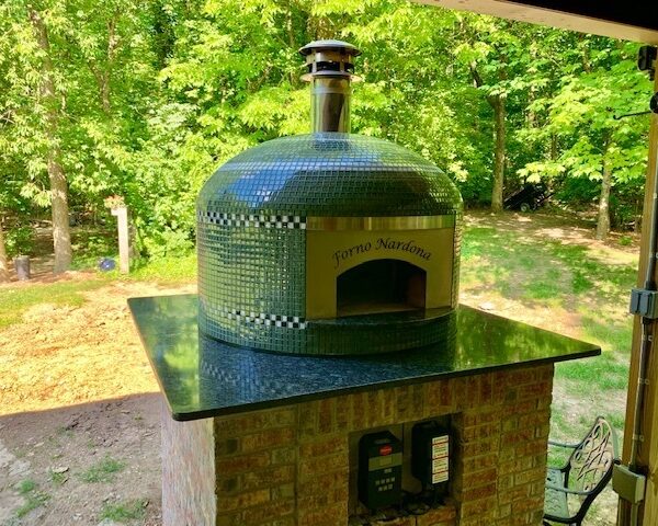 Forno Nardona Napoli glass-tiled wood-fired pizza oven on client built base of brick with granite countertop.