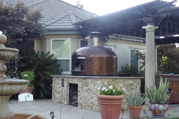 Forno Nardona Napoli pizza oven with copper glass tile sitting on top of a customer built base with stone and granite surfaces.