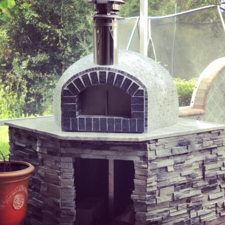 Nardona Rustico with black fire brick front, tiled exterior dome set on stone base with granite countertop.