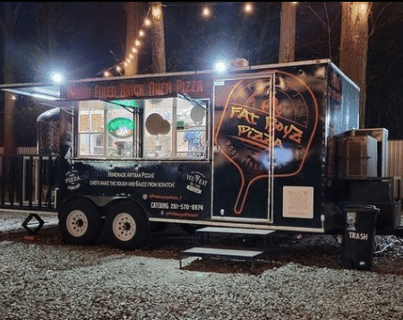 Outdoor photograph of a pizza trailer at nigh called Fat Boys Pizzsa